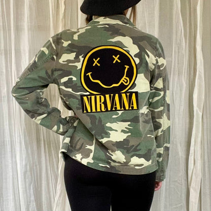 A woman wearing a camouflage jacket with a smiley face on it.
