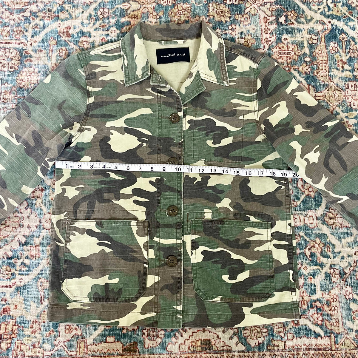 A camouflage jacket on a rug.