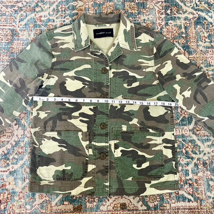 A camouflage jacket on a rug.