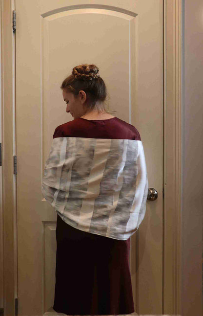 a woman standing in front of a door with a white and black scarf on her.