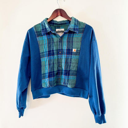 A blue and green plaid sweater hanging on a wall.