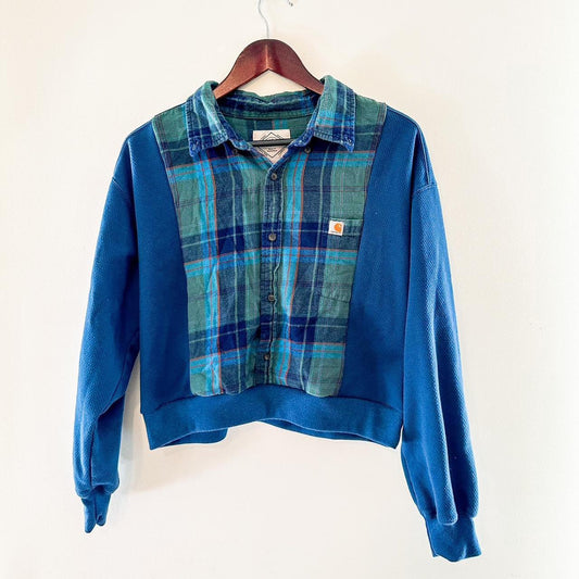 A blue and green plaid sweater hanging on a wall.