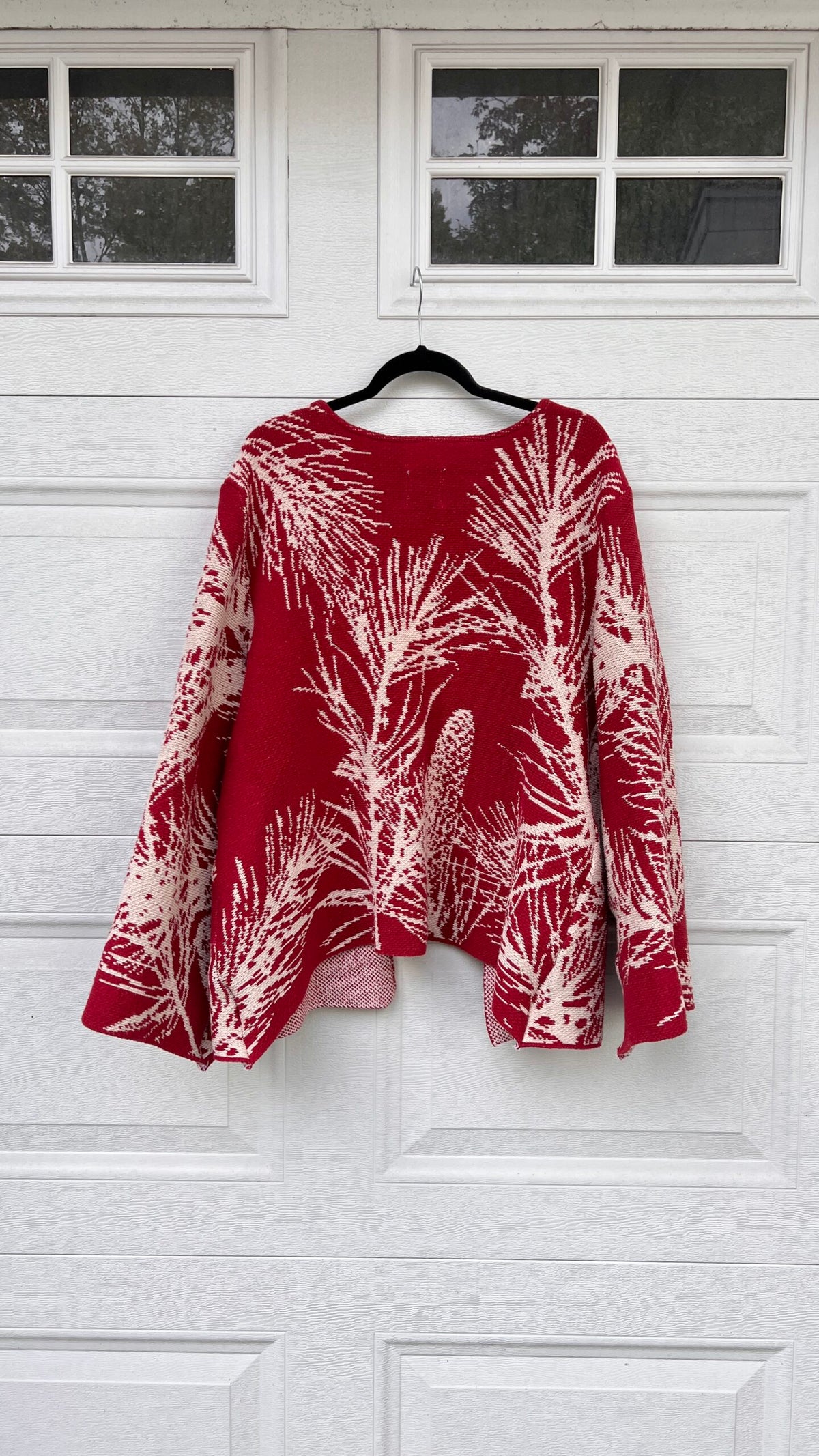 A red and white sweater hanging on a garage door.