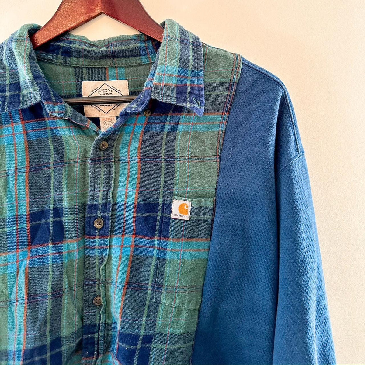 A blue and green plaid shirt hanging on a hanger.