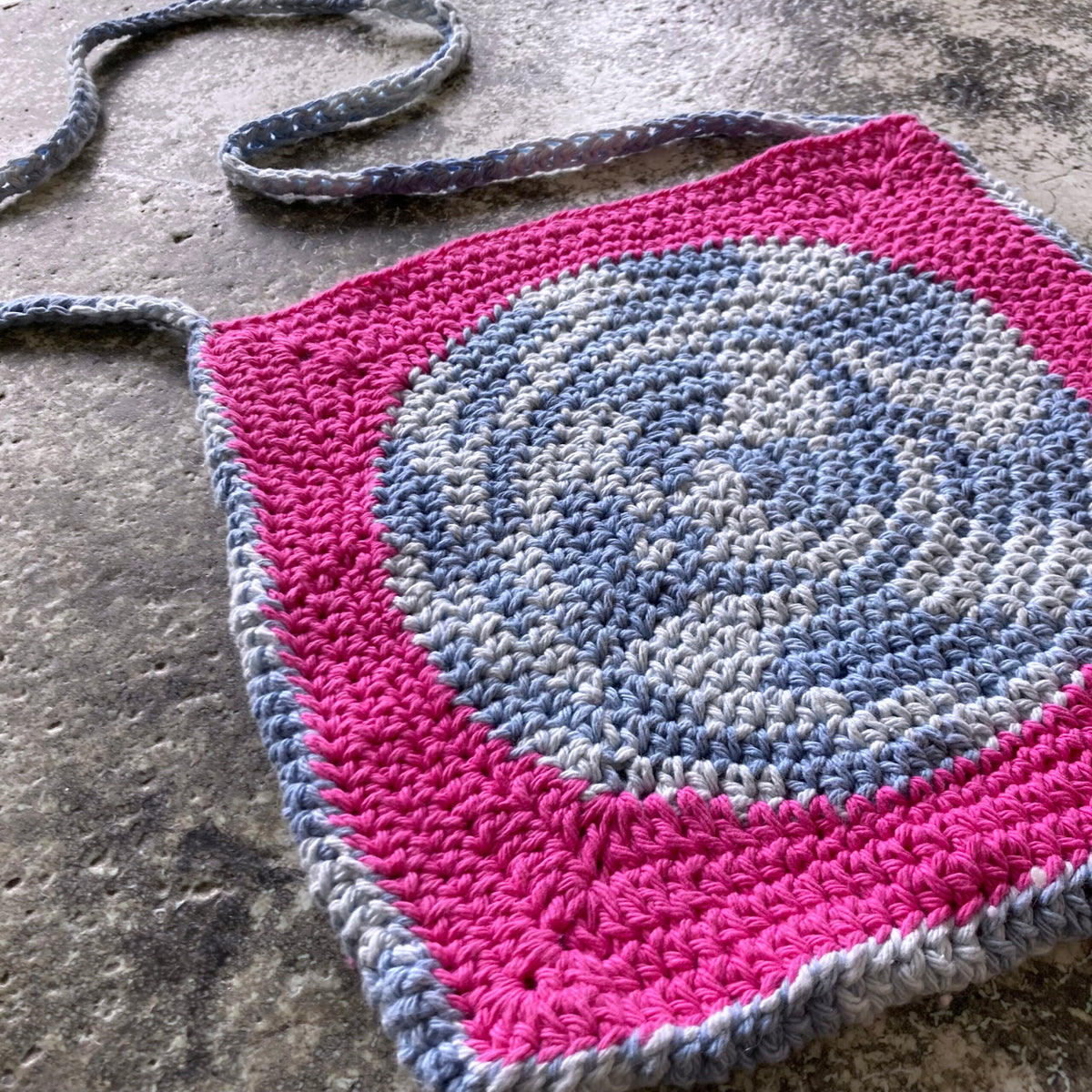 A crocheted bag with a pink and gray design.