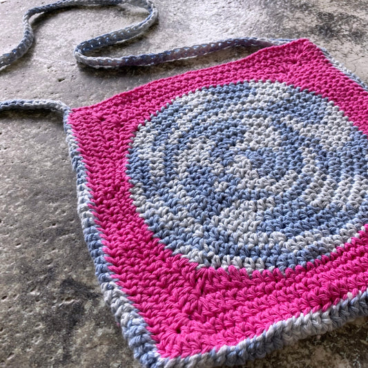A crocheted bag with a pink and gray design.