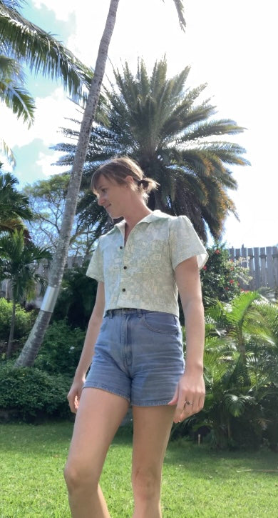 A woman in denim shorts standing in a grassy area.