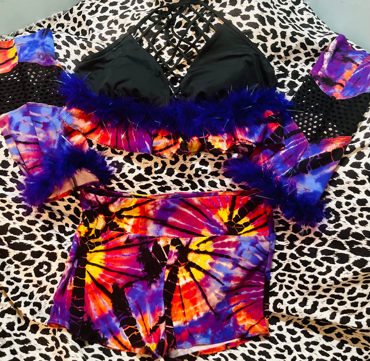 A colorful tie dye bikini set on a leopard print bed.