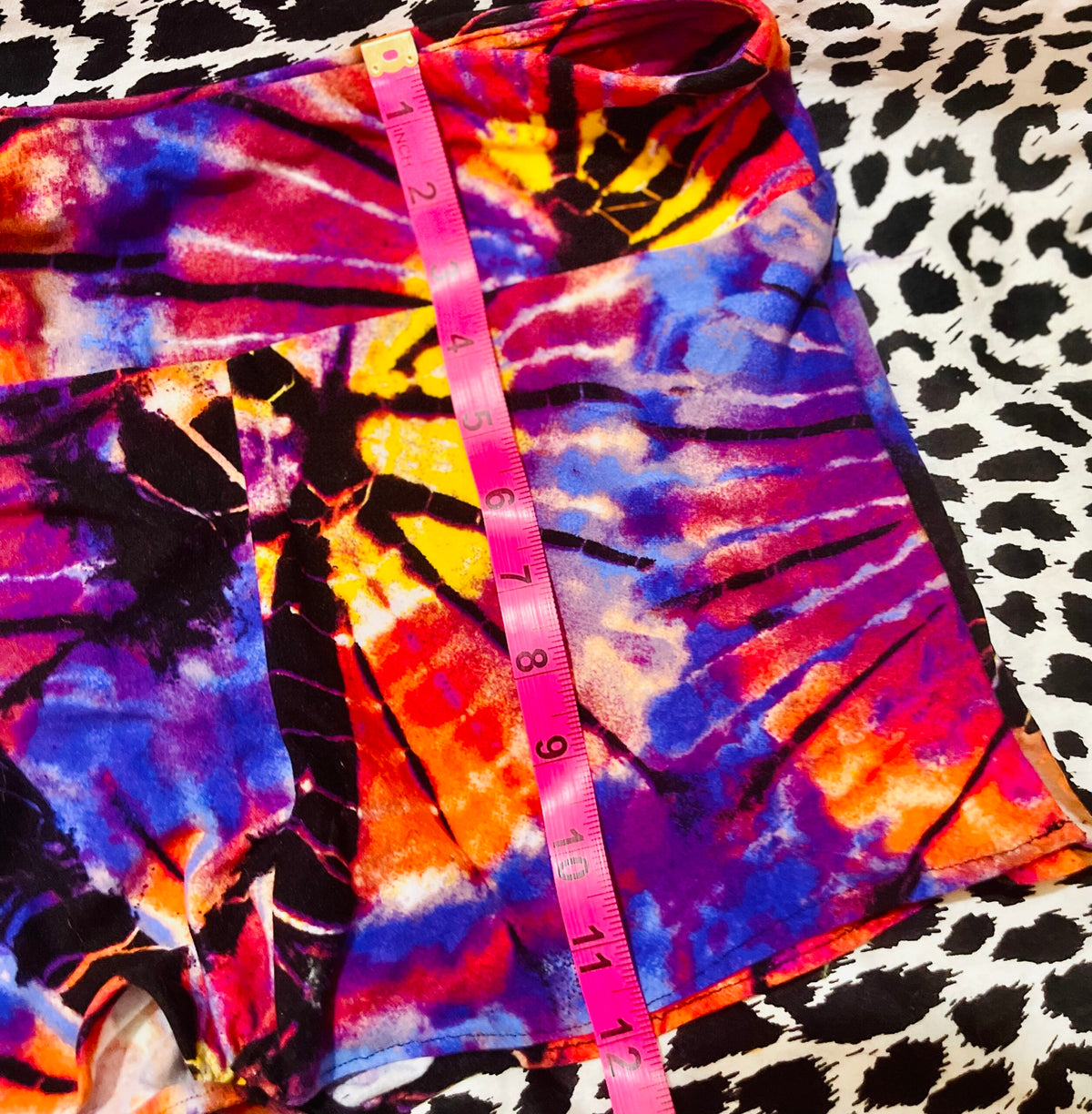A pair of tie dye shorts with a measuring tape.