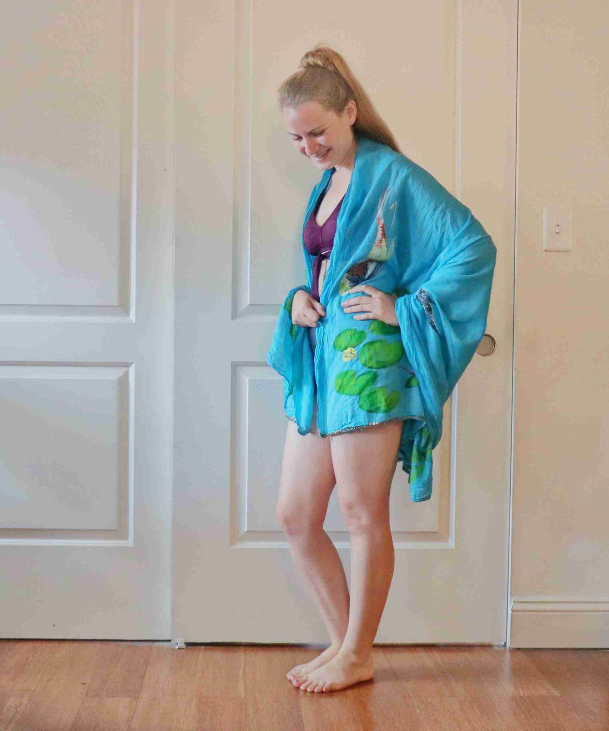 a woman standing in front of a door wearing a blue robe.