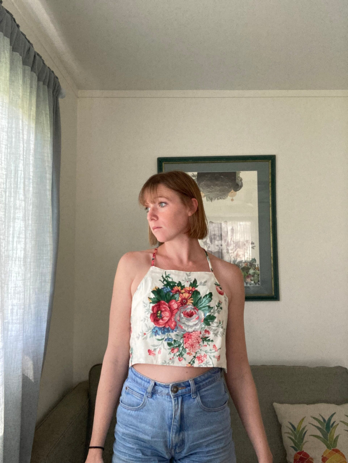A woman standing in a living room wearing a floral top.