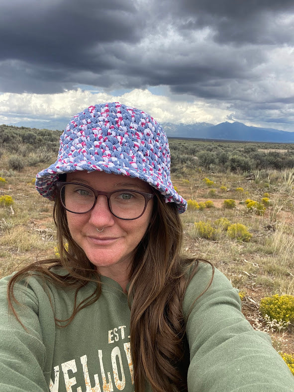 A woman wearing a bucket hat in the desert.