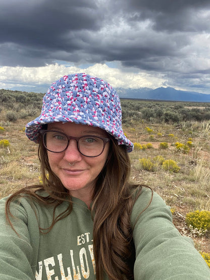 A woman wearing a bucket hat in the desert.