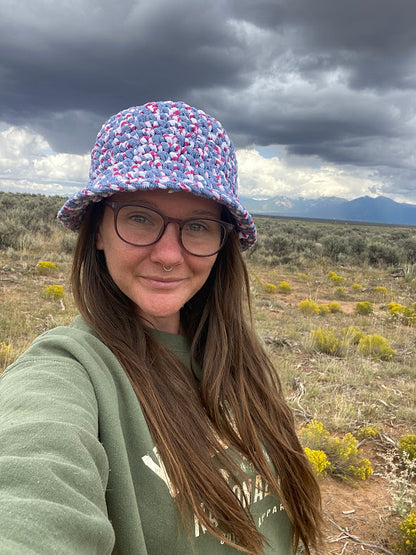 A woman wearing glasses and a hat in the desert.