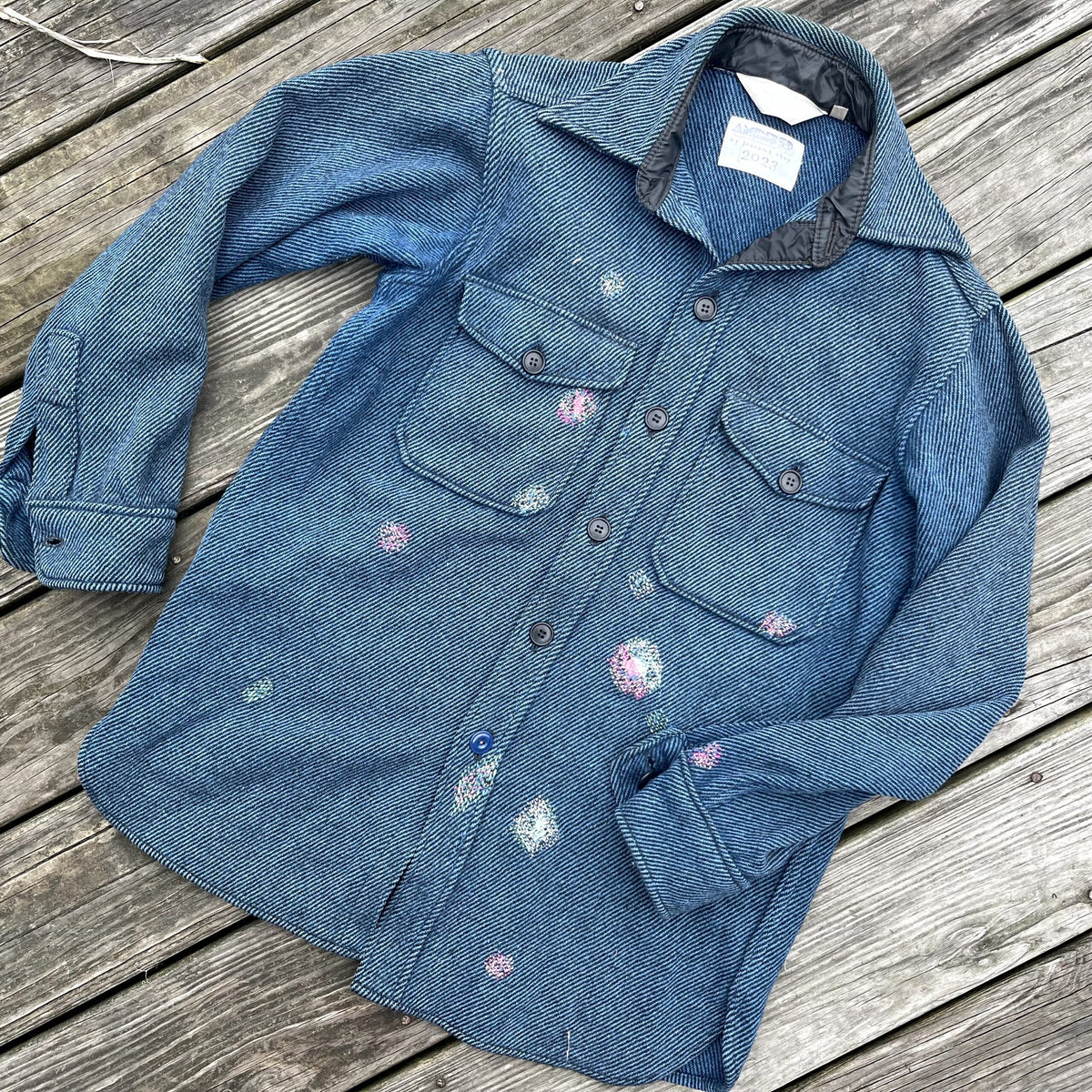 A blue denim shirt with paint splatters on it.