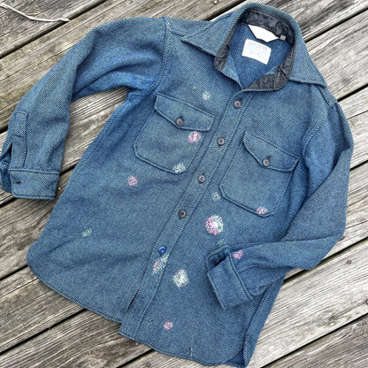 A blue denim shirt with paint splatters on it.