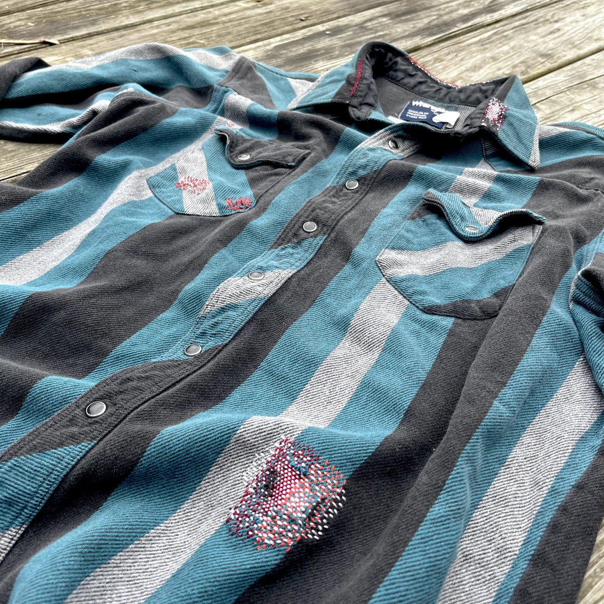 A blue and grey striped shirt on a wooden floor.