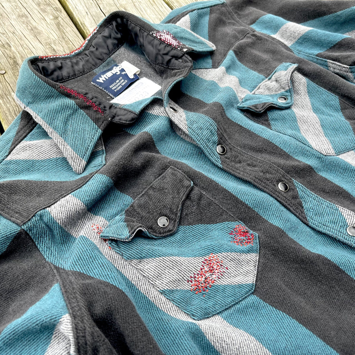 A blue and grey striped shirt on a wooden deck.