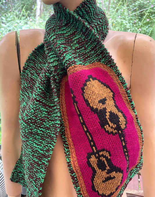 A mannequin wearing a knitted scarf with a guitar on it.