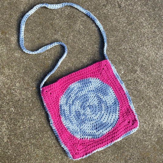 A crocheted bag with a blue and pink design.