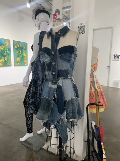 a mannequin wearing a denim dress in an art gallery.