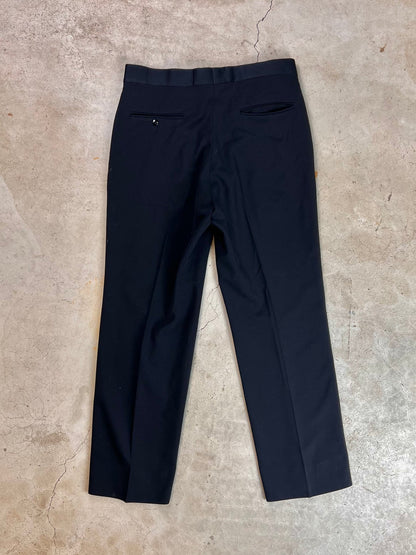 A pair of navy blue dress pants laid flat on a concrete surface.
