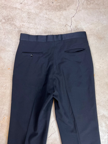 Black trousers laid out on a textured surface.