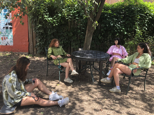 A group of women sitting around a black table while wearing Cool as a Cucumber.