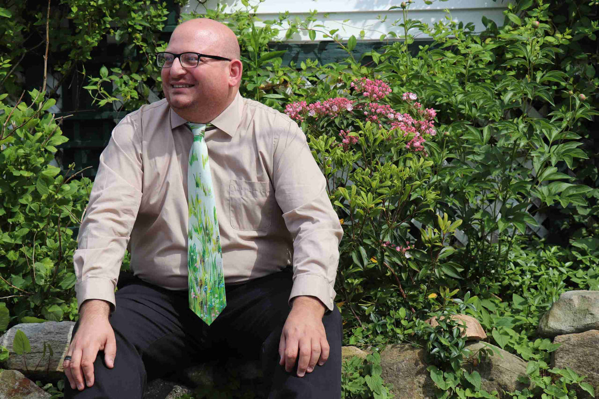 a man wearing a tie sitting on a rock.