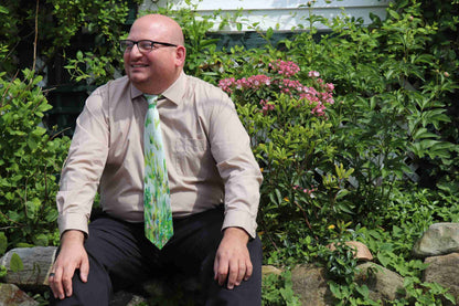 a man wearing a tie sitting on a rock.