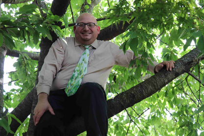 a man sitting in a tree wearing a tie.