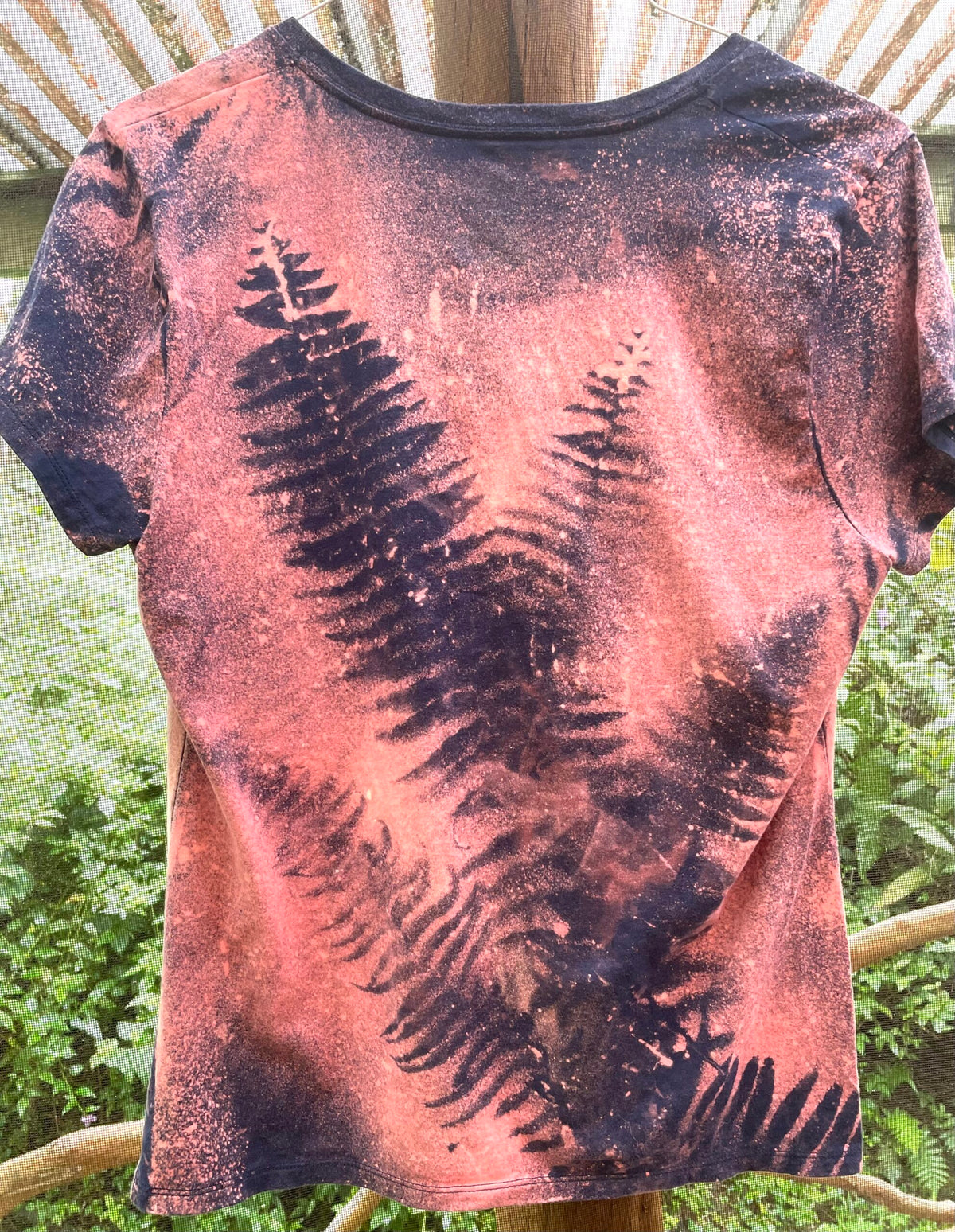 The back of a women's t - shirt with fern leaves on it.