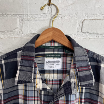 A plaid shirt hanging on a white brick wall.