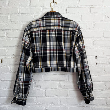 A black and white plaid jacket hanging on a brick wall.