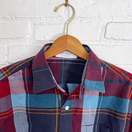 A plaid shirt hanging on a white brick wall.