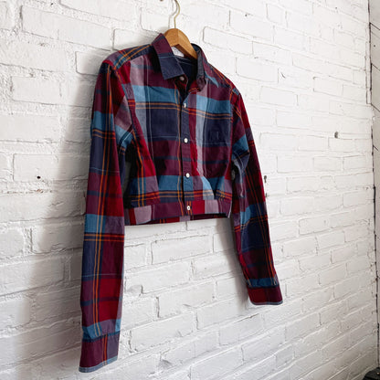 A red and blue plaid shirt hanging on a brick wall.