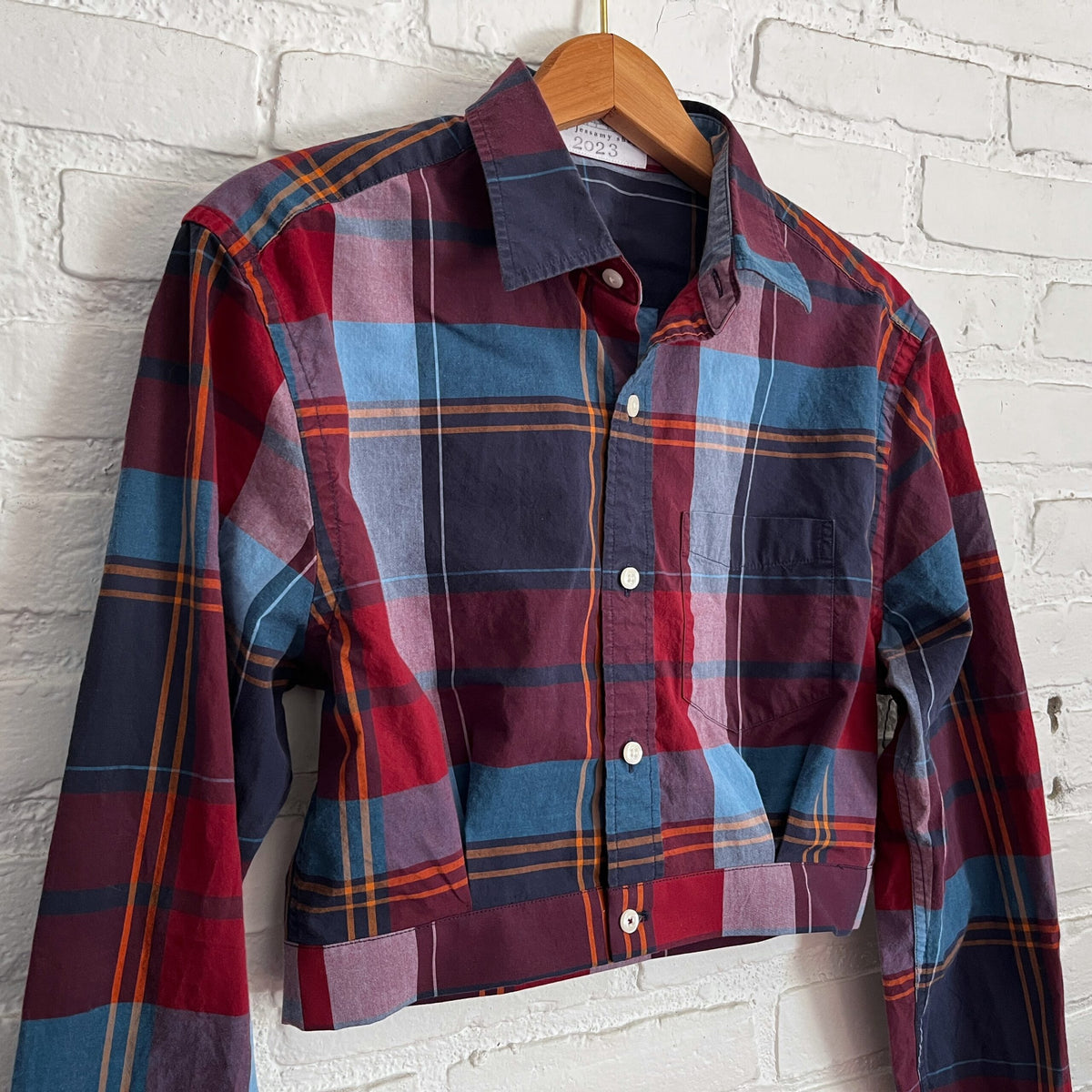 A plaid shirt hanging on a brick wall.