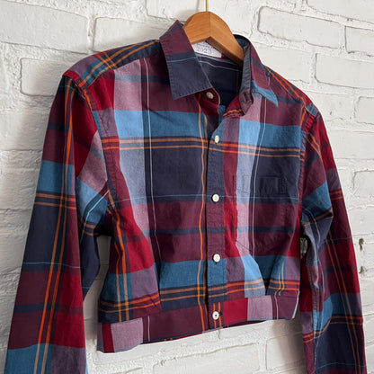A plaid shirt hanging on a brick wall.
