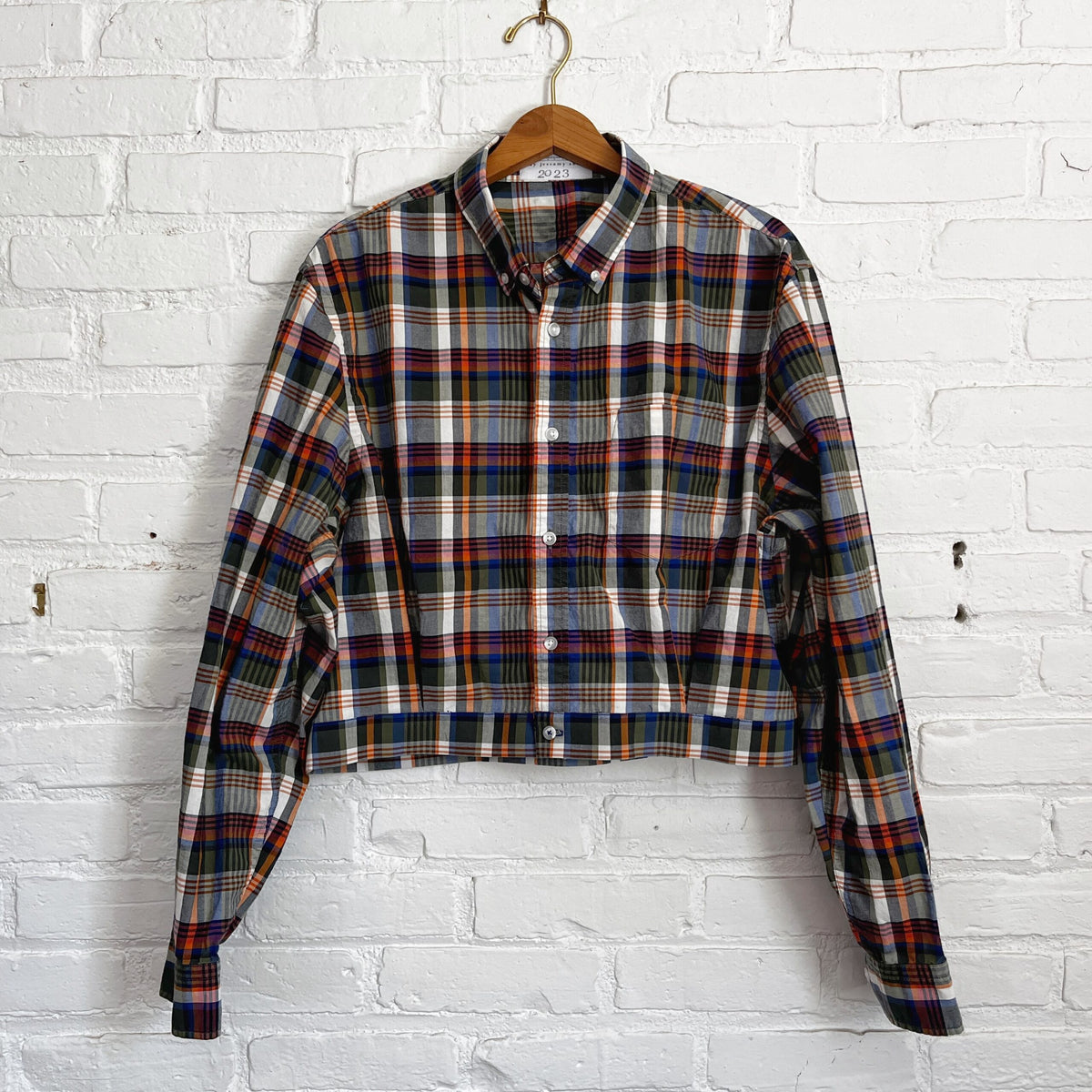 A plaid shirt hanging on a brick wall.