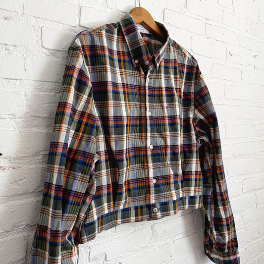 A plaid shirt hanging on a brick wall.
