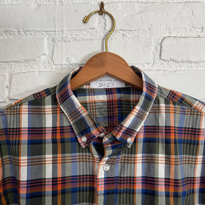 A plaid shirt hanging on a white brick wall.