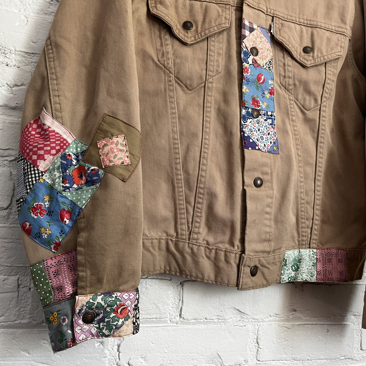 A denim jacket with patchwork patches on it.