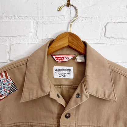A tan jacket hanging on a brick wall.