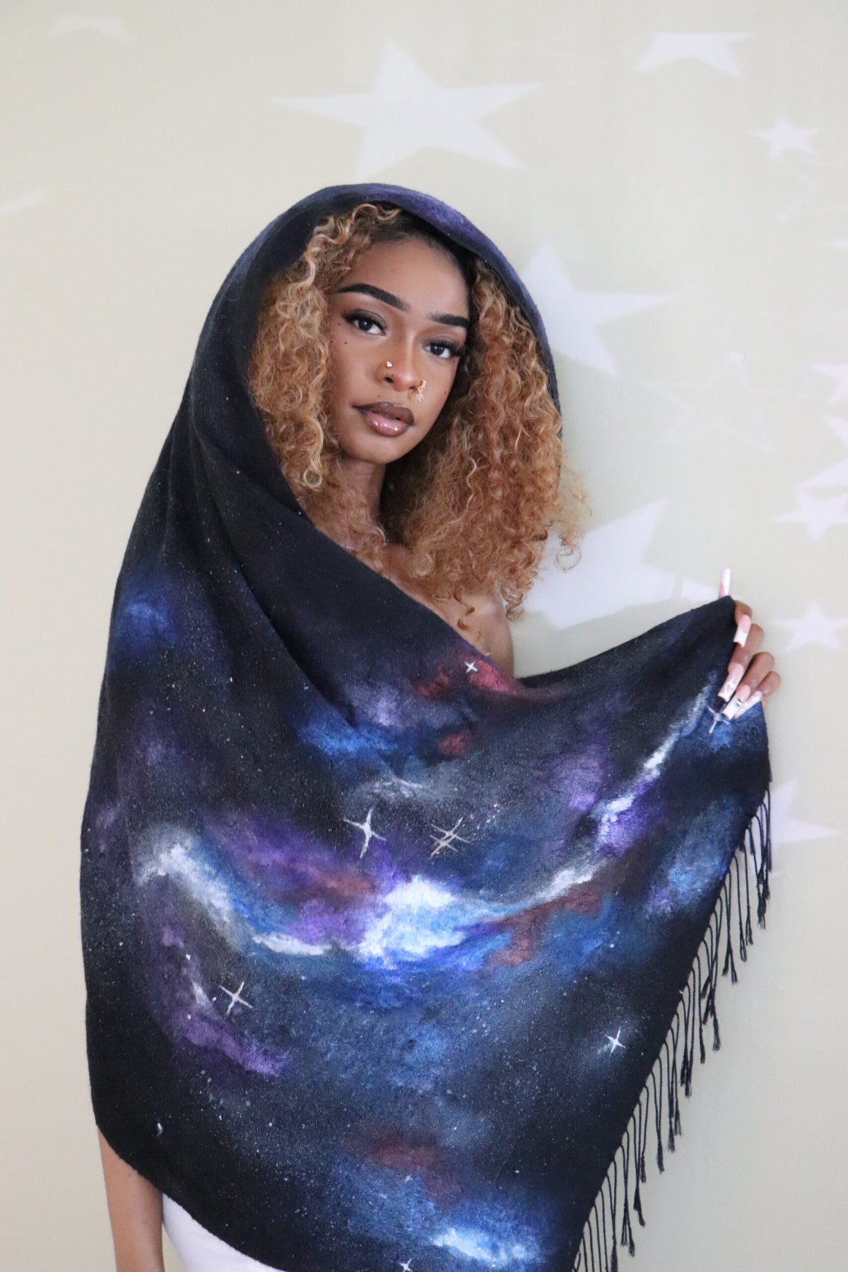 woman wearing a scarf and showing the hand-painted space design on the end