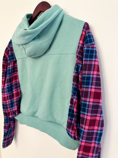 A blue and pink plaid hoodie hanging on a hanger.