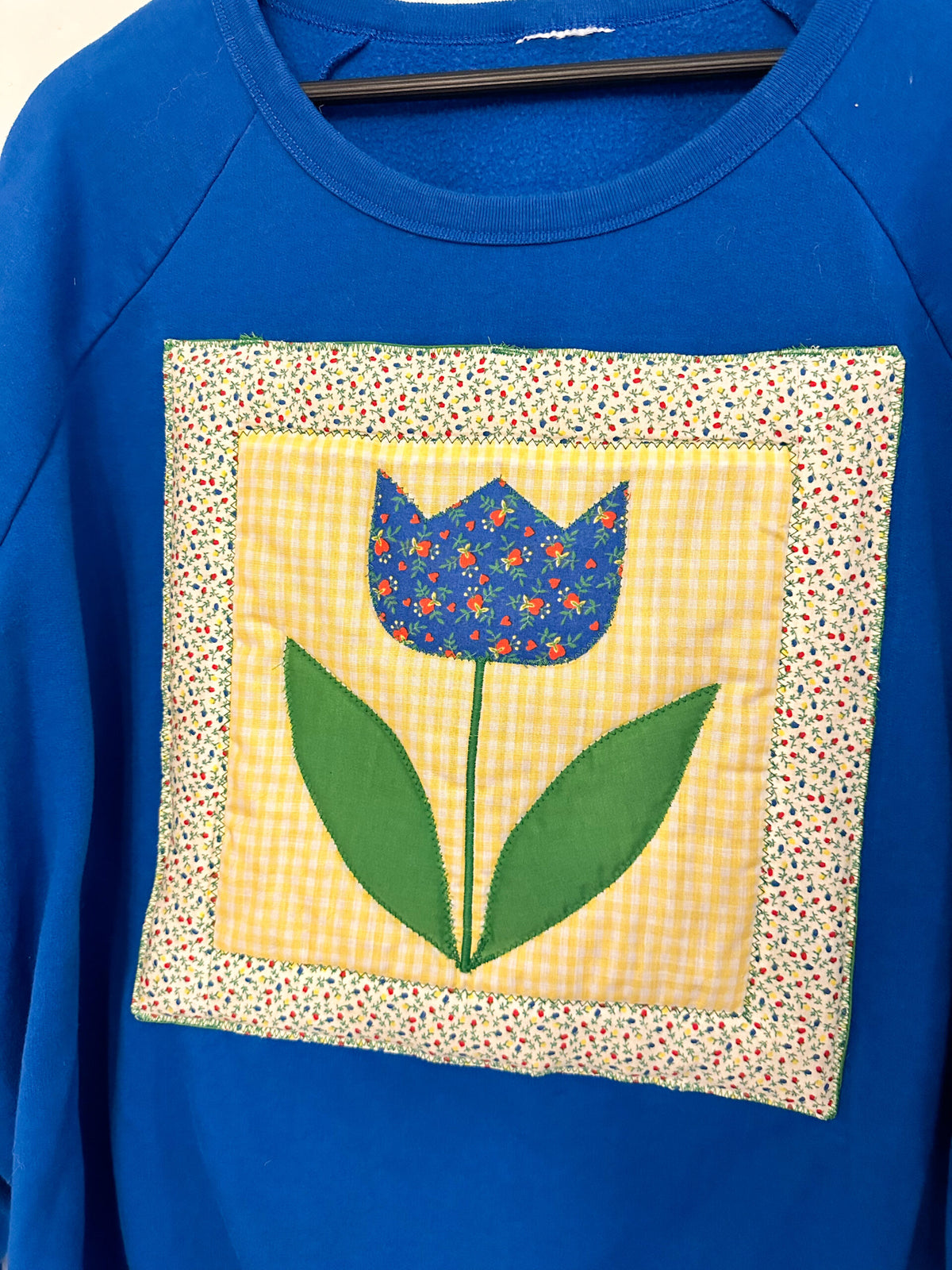 A blue sweatshirt with a flower on it.