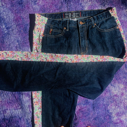 a pair of jeans sitting on top of a purple blanket.