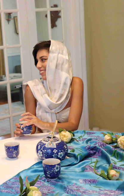 a woman sitting at a table with a blue vase.