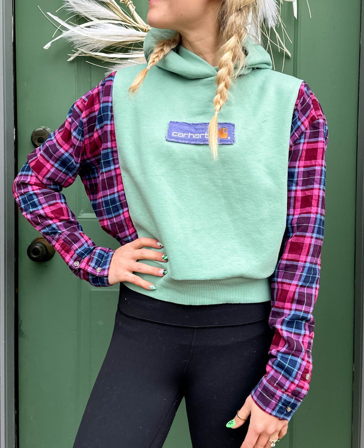 A woman wearing a green and pink plaid hoodie.