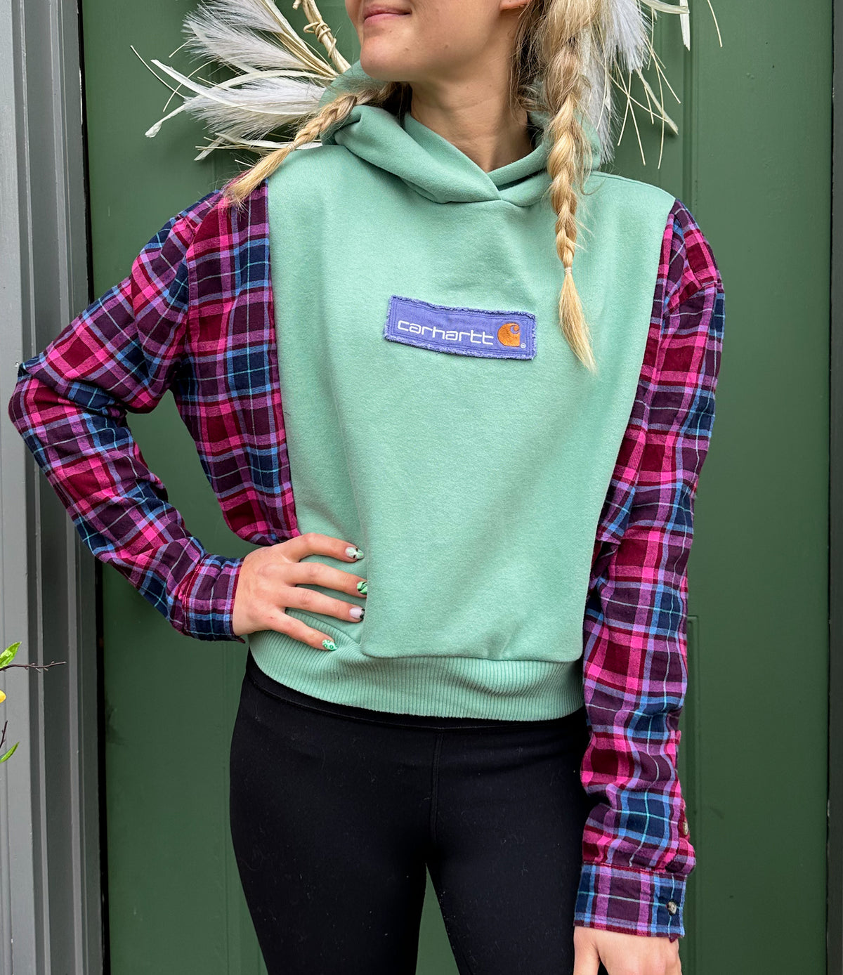 A young woman wearing a green plaid hoodie.